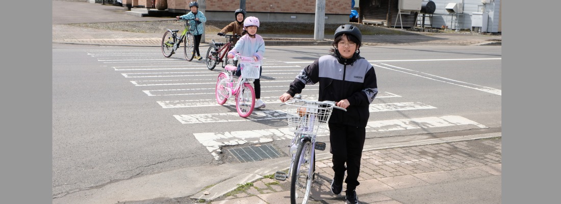小学校生徒4人が自転車を押して横断歩道を渡っている様子　交通安全教室の1シーン